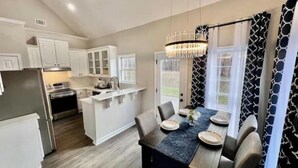 A modern kitchen with white cabinets, a central island, and a dining area with a table set for four.