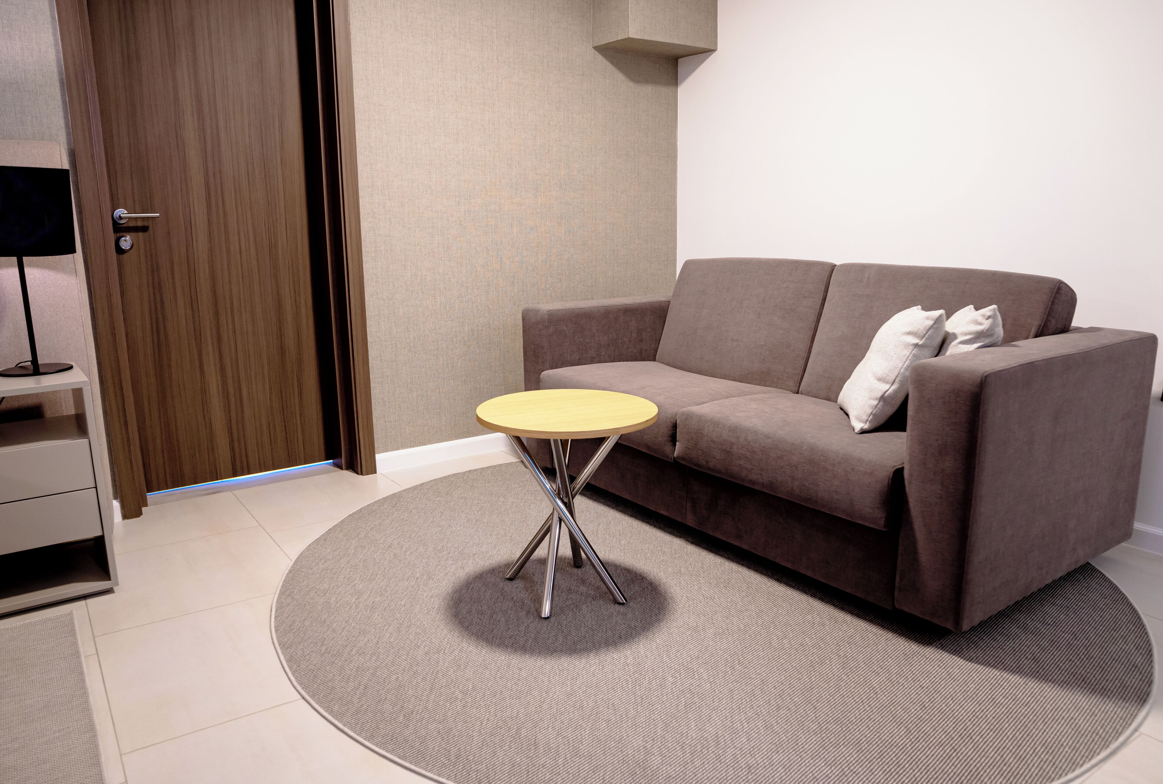 Un salon moderne avec un canapé marron, une petite table ronde et un téléviseur posé sur un meuble.
