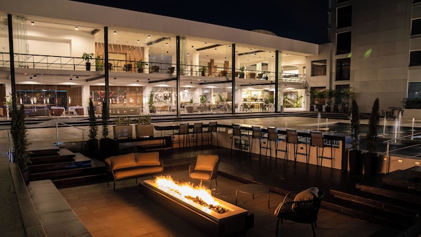 Ein moderner Außenbereich mit Lounge-Möbeln, einem Kamin und einer Bar.