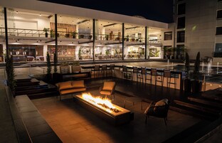 Uma área de estar ao ar livre moderna com lareira, assentos e bar.