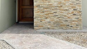 Un edificio moderno con fachada de piedra, puerta de madera y un logotipo con una piña.