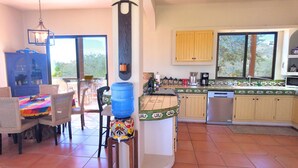 Une cuisine avec un coin repas, un distributeur d’eau et une vue par la fenêtre.