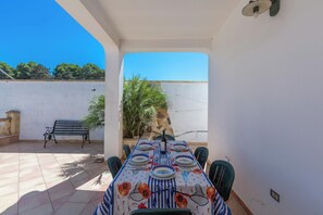 Enjoy meals al fresco in this charming outdoor dining area with a long table and comfortable seating.