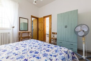Cozy retreat with a large bed, wooden wardrobe, and standing fan.