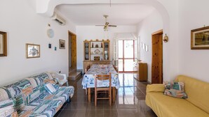 A spacious living area with a sofa, a yellow couch, a dining table with chairs, and a wooden cabinet with decorative items. - 4173 Villetta Ambra by Barbarhouse (Porto Cesareo)