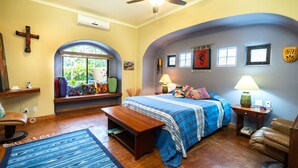 A bedroom with a bed, a desk, a chair, a window, and a ceiling fan.
