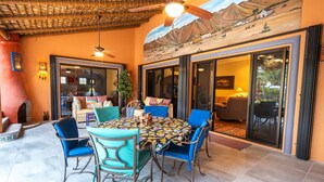 A patio area with a round table, blue chairs, and a ceiling fan.