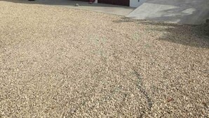 Un edificio moderno de dos plantas con techo plano, ventanas amplias y entrada de grava.