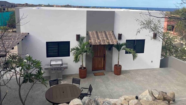 Un patio con una parrilla, asientos y plantas en macetas.