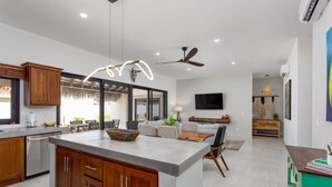 A modern kitchen with wooden cabinets, a central island, and a dining area with a sofa and table. - Walkable Convenient in Downtown Los Barriles (Los Barriles)