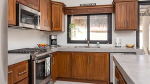A kitchen with wooden cabinets, stainless steel appliances, a large window, and a sign above the window. - Walkable Convenient in Downtown Los Barriles (Los Barriles)
