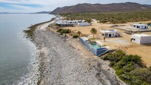 A coastal resort with multiple white buildings, a swimming pool, and a beach.