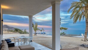 A covered outdoor seating area with a view of the beach and ocean.