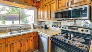 A kitchen with wooden cabinets, a stainless steel microwave, a stove, and a dishwasher. - Updated Damascus Cottage on Appalachian Trail! (Damascus)