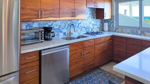 Una cocina moderna con armarios de madera, un refrigerador de acero inoxidable, horno empotrado y salpicadero con diseño.