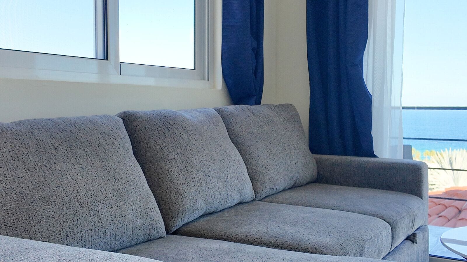 Un divano grigio in una stanza con una finestra e tende.
