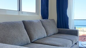 Un sofá gris en una habitación con ventana y cortinas.
