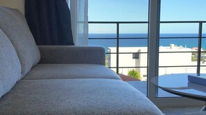 Un salón moderno con sofá y una mesita, con vistas despejadas al mar.