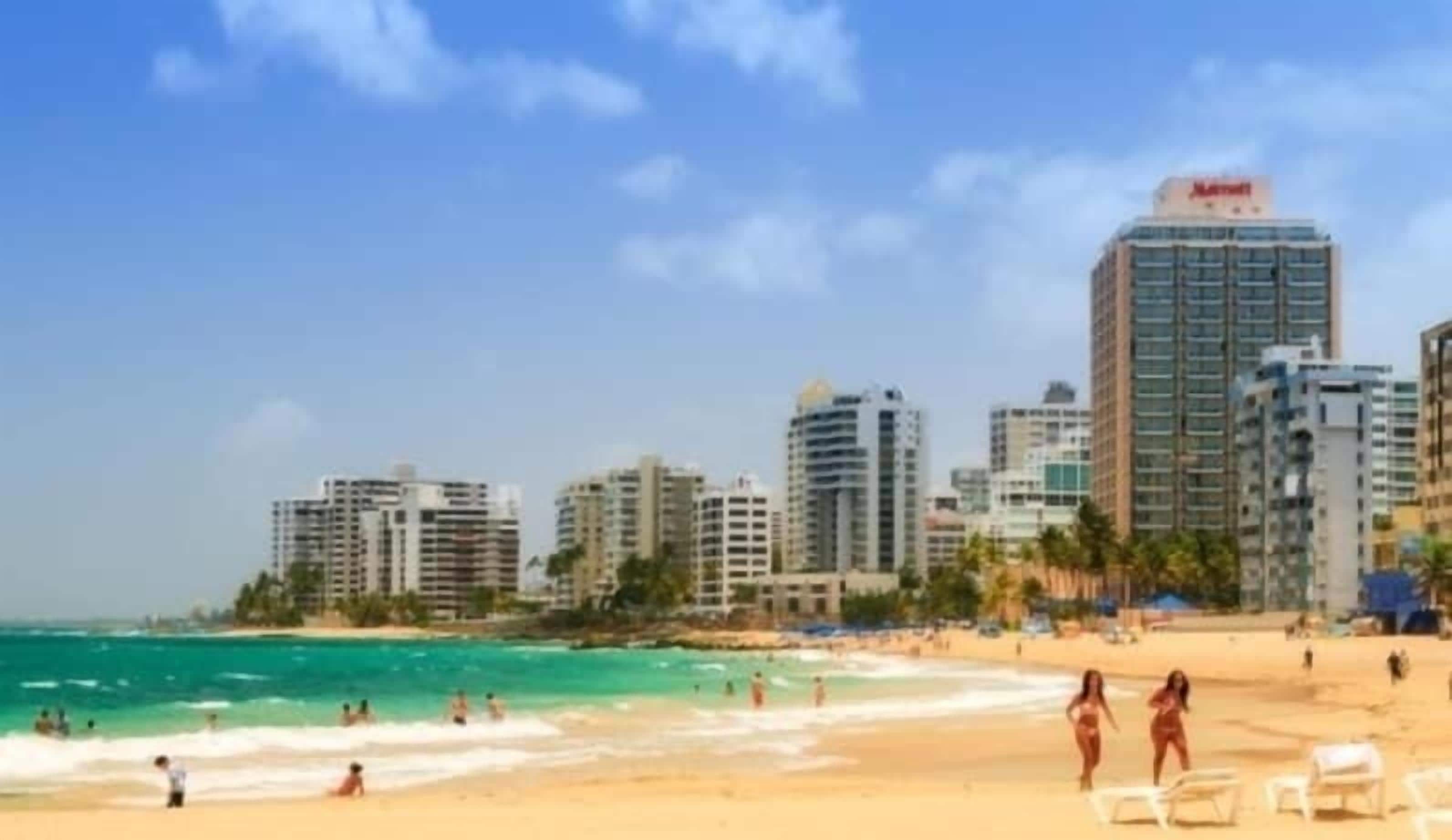 Ein Strand mit Stadtansicht im Hintergrund, darunter ein Marriott Hotel.
