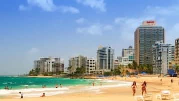 A beach with a city skyline in the background, including a Marriott hotel.