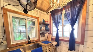 Una cocina con armarios de madera, un lavamanos y una ventana con cortinas azules.