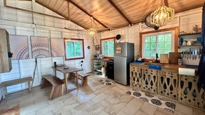 A rustic kitchen with wooden walls, a central island, and a dining area with benches. - Casa Serenity By The Sea Reef House  (Bocas Del Toro)