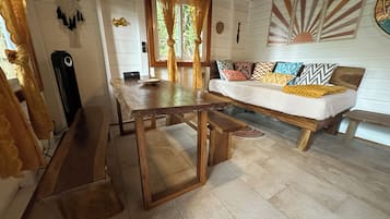 A cozy living room with a wooden table and bench, a sofa with patterned cushions, and a wall with decorative elements.