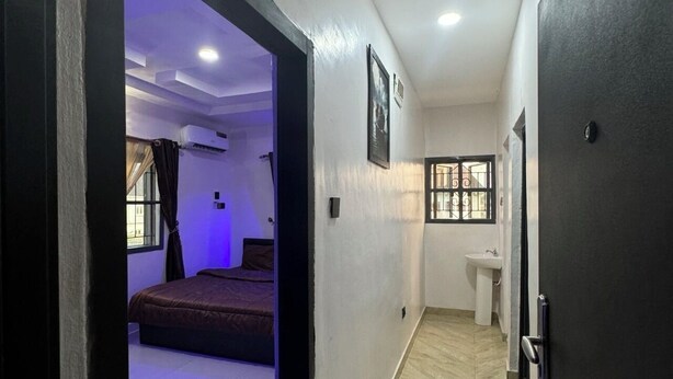 A hotel room with a bed, a window, a sink, and a door. - Cozy 1-BEDROOM WITH AC, WiFi, FULL kitchen, free parking, restaurant delivery (Satellite Town)