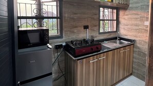 A kitchen with wooden cabinets, a gas stove, a microwave, and a sink. - Cozy 1-BEDROOM WITH AC, WiFi, FULL kitchen, free parking, restaurant delivery (Satellite Town)