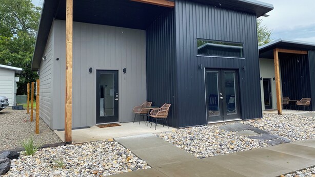 A modern two-story building with a grey exterior and wooden accents.