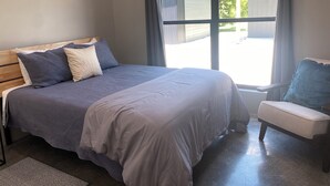 A bedroom with a bed, a chair, and a window.