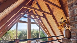 Una habitación con techo de madera inclinado, ventanas amplias y pared de ladrillo.