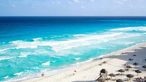 A beach with clear turquoise water, white sand, and thatched umbrellas. - Alberca privada con cascada familia/amigos

 (Cancún)