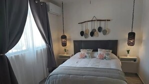 A bedroom with a bed, dark curtains, a wall-mounted air conditioner, two bedside tables with lamps, and a ceiling fan. - Alberca privada con cascada familia/amigos

 (Cancún)