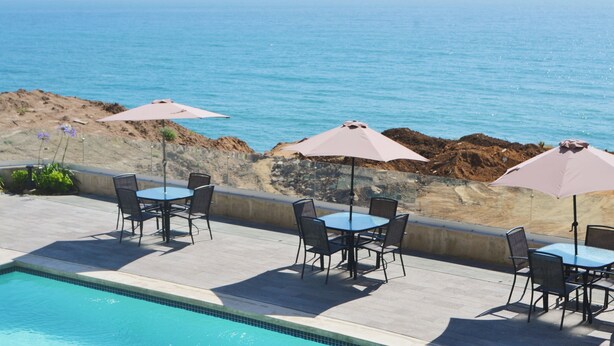 Zona junto a la piscina con mobiliario exterior y vista al océano.