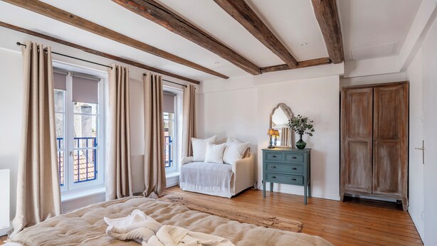 A bedroom with a large bed, a bedside table with a lamp, a dresser, and a wardrobe. - Rock in Share - A la Fleur de Ly (Metz)