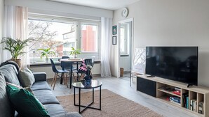 A modern living room with a sofa, TV, and dining area. - Bright & Cozy, Renovated Studio in the Center (Lahti)