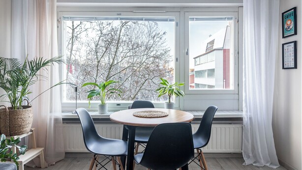 A dining area with a round table, four chairs, and two potted plants. - Bright & Cozy, Renovated Studio in the Center (Lahti)