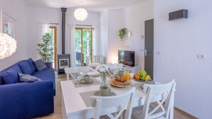 Una sala de estar moderna con sofá, mesa de comedor, sillas, televisor y chimenea.