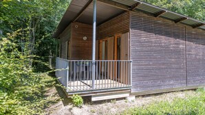 Una cabaña de madera con balcón, rodeada de árboles.