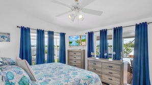 A bedroom with a bed, a dresser, a television, and a view of the outdoors. - Charming 3-bedroom 2-bathroom house with Boat Ramp and Dockage in Marathon (Marathon)