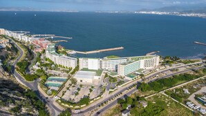 An aerial view of a coastal hotel with multiple buildings, a marina, and a road network.