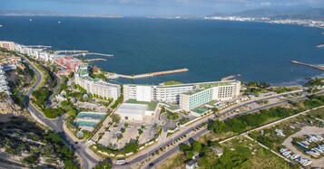 Vista aérea de um hotel à beira-mar, com vários edifícios, uma marina e uma rede de estradas.
