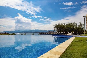 Piscina com vista ampla do céu e montanhas ao fundo.