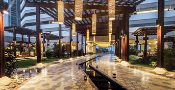 A covered outdoor area with a patterned floor, hanging lights, and a view of a building in the background.