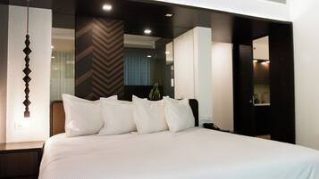 Ein modernes Hotelzimmer mit einem großen Bett, einem Nachttisch, einem Spiegel und einer Wand mit geometrischem Muster.