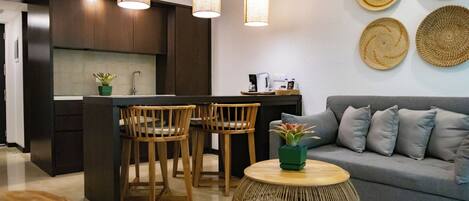 A modern kitchen with dark wood cabinets, a central island with chairs, and pendant lighting.