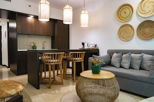 Cozinha moderna com armários de madeira escura, uma ilha central com cadeiras e iluminação pendente.