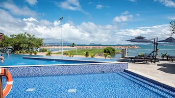 Una piscina al aire libre, sombrillas, sillones reclinables de piscina