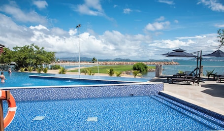 Una piscina al aire libre, sombrillas, sillones reclinables de piscina